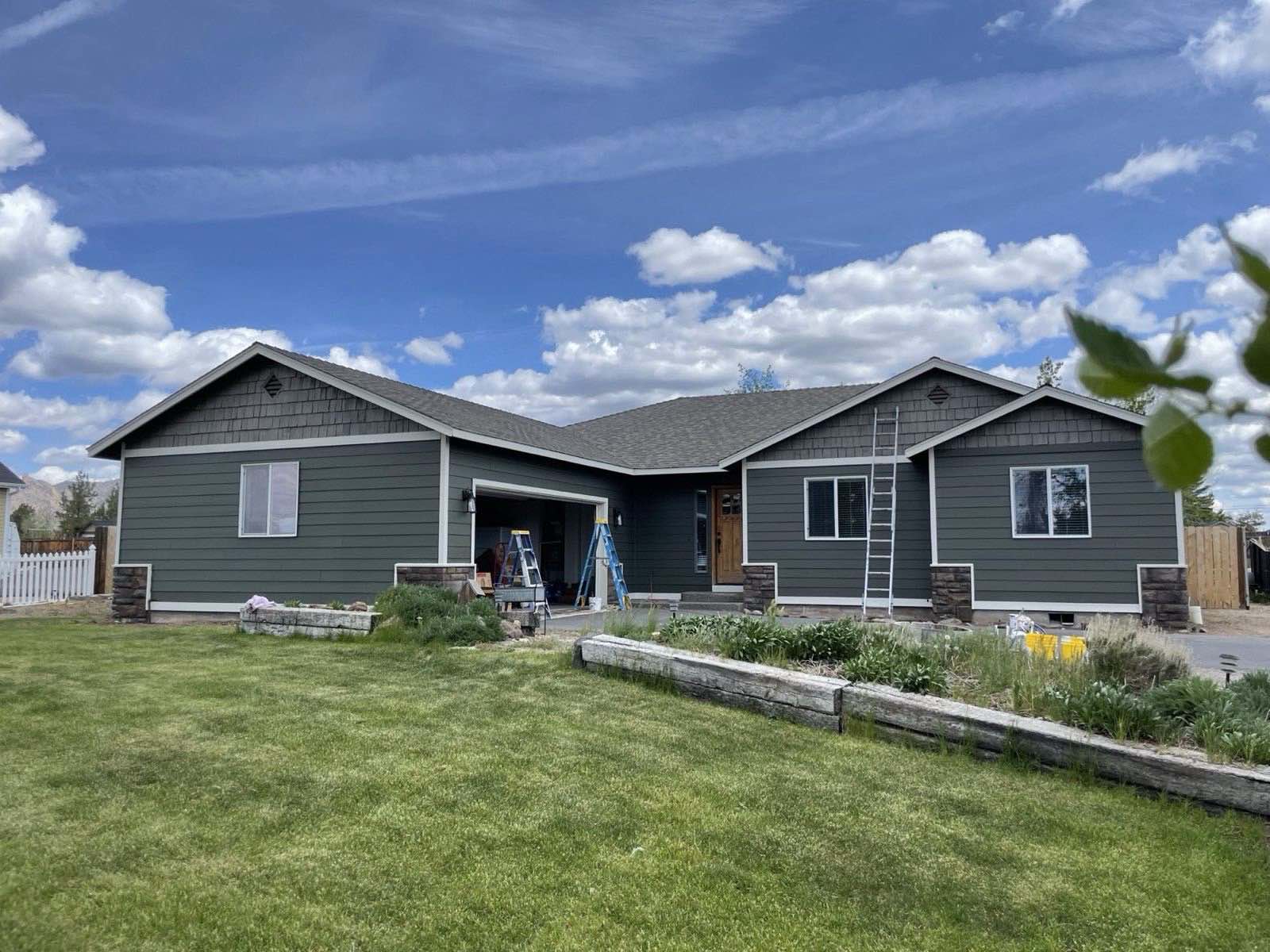 Three-tone exterior repaint in deep green with white trim and repainted gables by Keystone Painting LLC in Terrebonne, Oregon