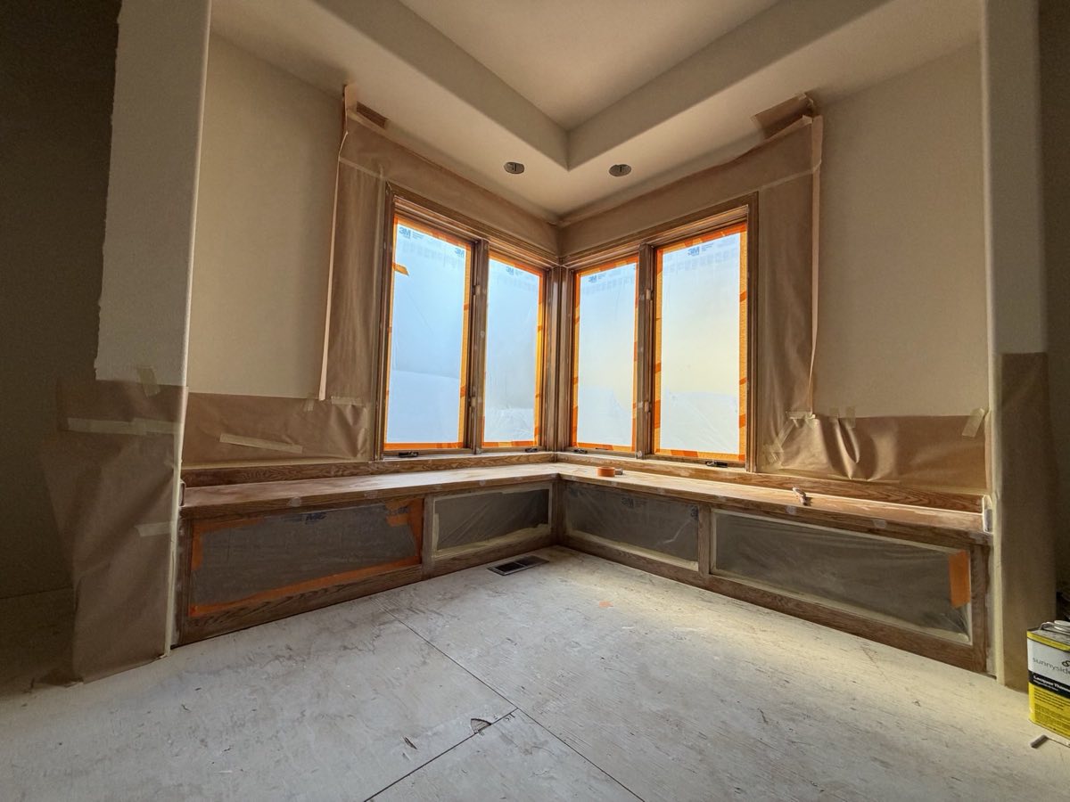 Clear-coated oak window seat and bay window trim masked and prepped for a stain-to-paint conversion by Keystone Painting LLC in Bend, Oregon