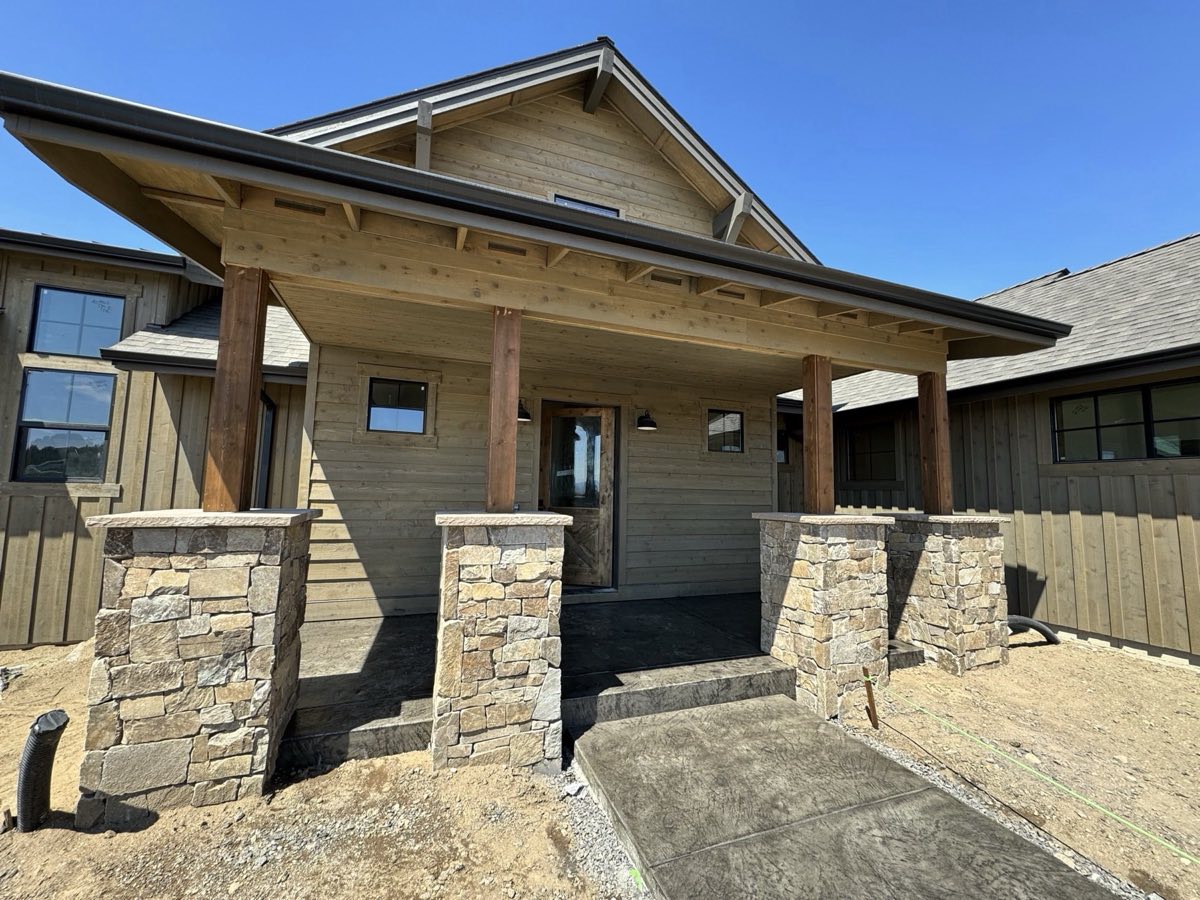 Custom home exterior at Brasada Ranch in Powell Butte, Oregon, with board-and-batten siding and timber posts sprayed and backrolled in stain by Keystone Painting LLC