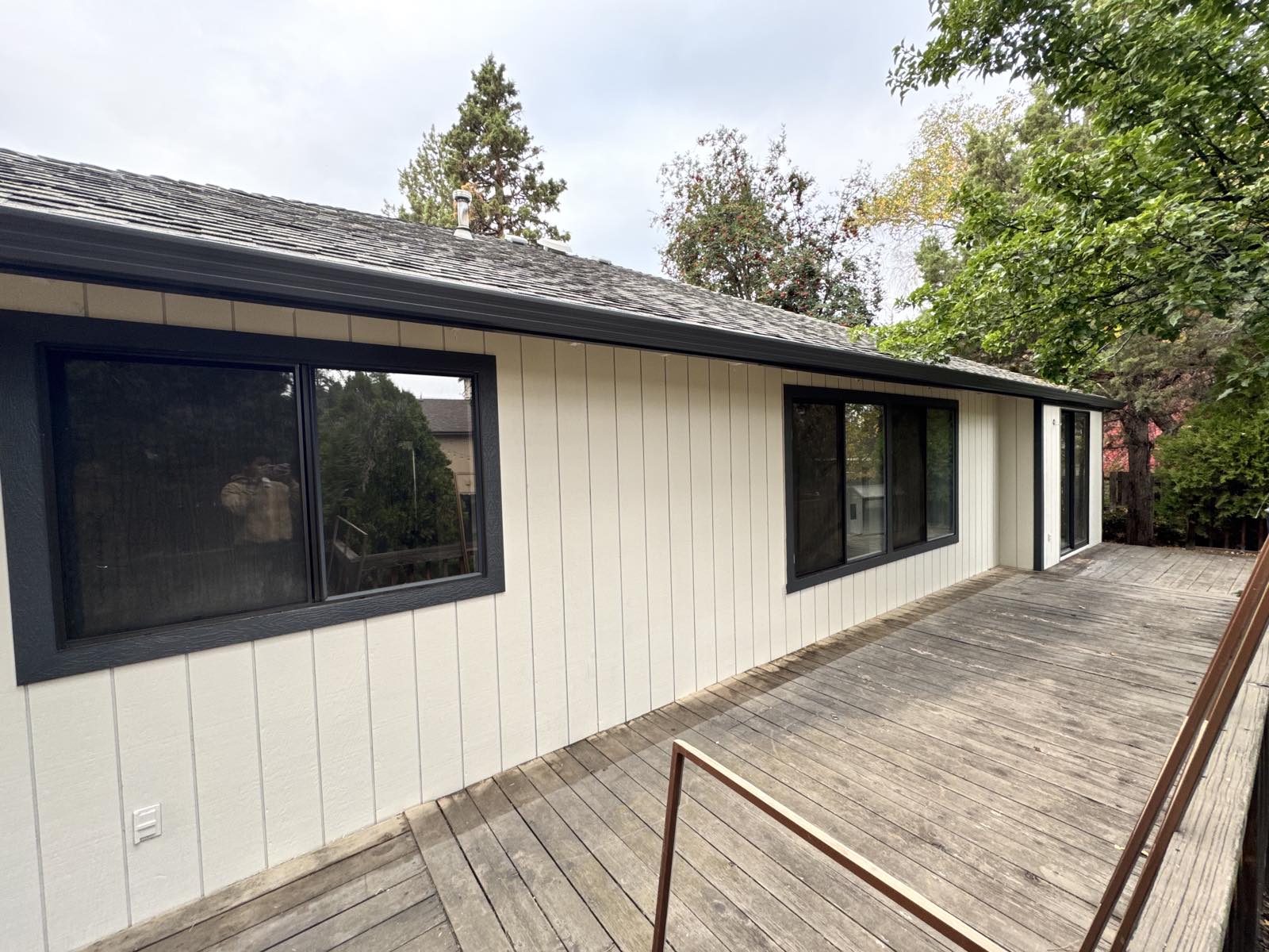 Deck-side elevation of the same Bend, Oregon home after a Keystone Painting LLC exterior repaint, in a bright off-white body with charcoal window trim and fascia