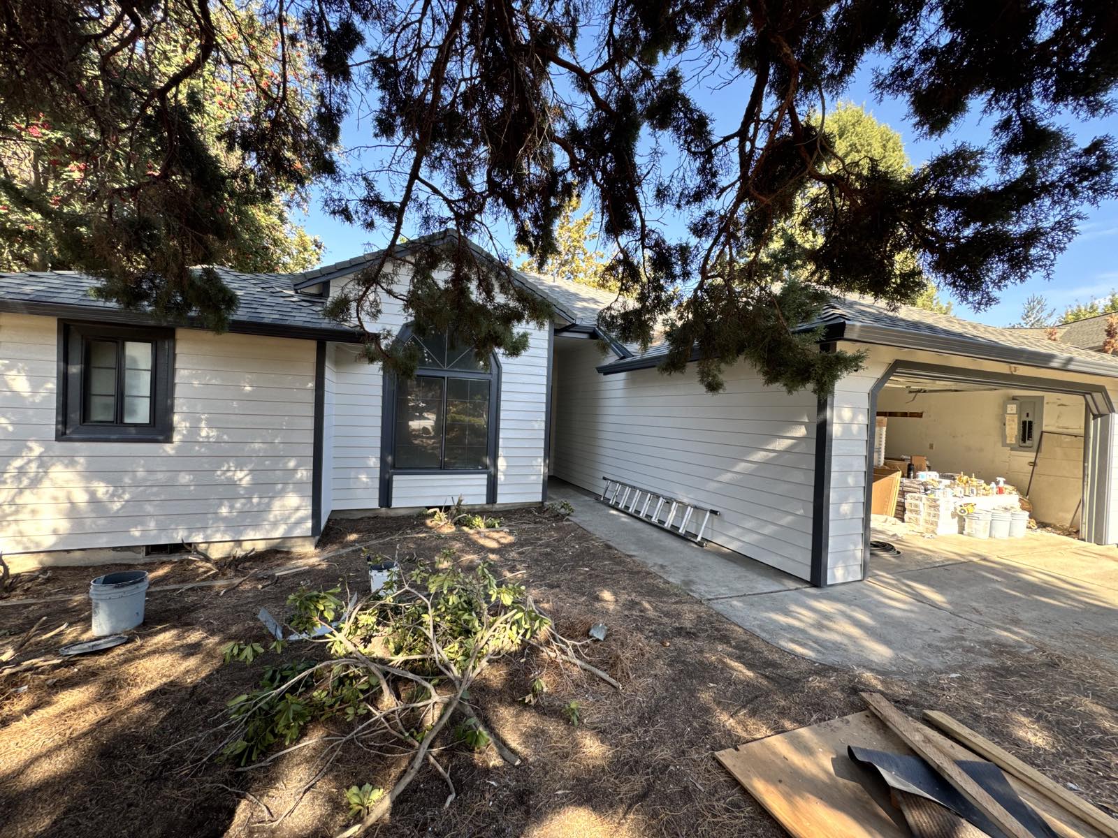 Front elevation of the same Bend, Oregon home after a Keystone Painting LLC exterior repaint, in a bright off-white body with charcoal trim, the garage left unpainted because the client was replacing it