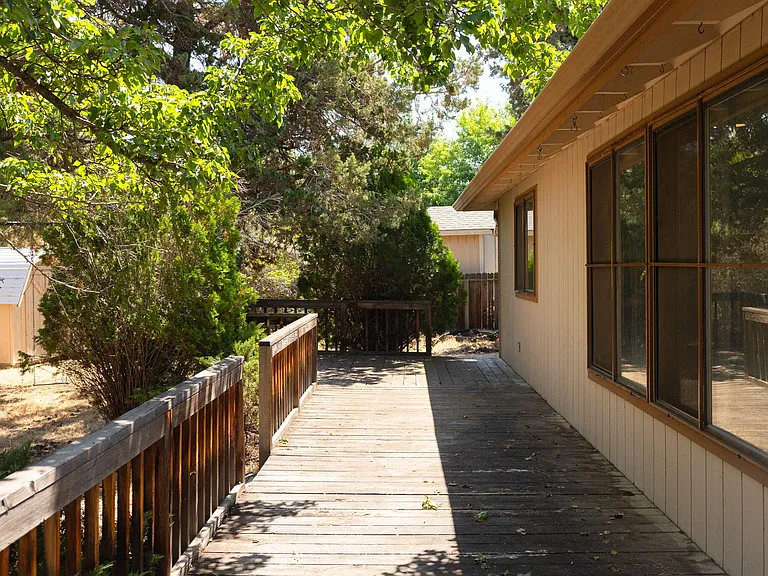 Deck-side elevation of a Bend, Oregon home before repainting, in the original tan siding and trim