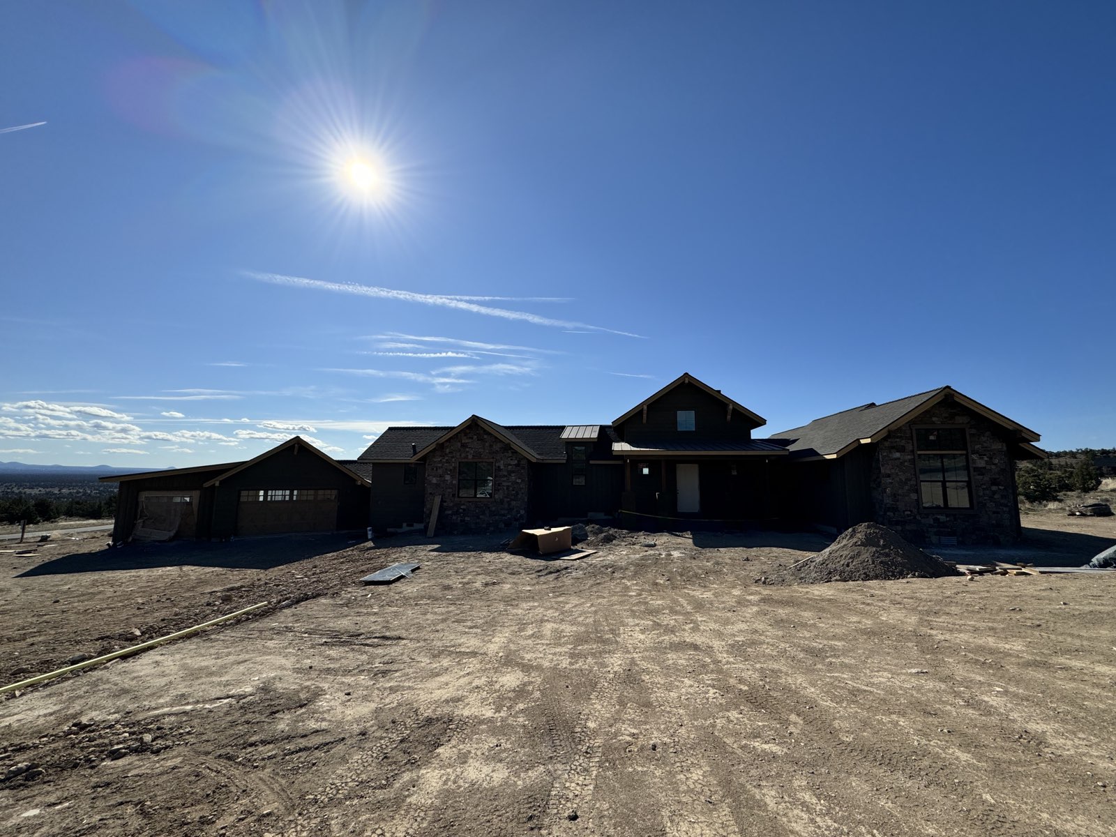 Custom lodge-style home at Brasada Ranch in Powell Butte, Oregon, with dark-stained board-and-batten siding, timber brackets and stone veneer, sprayed and backrolled in stain by Keystone Painting LLC