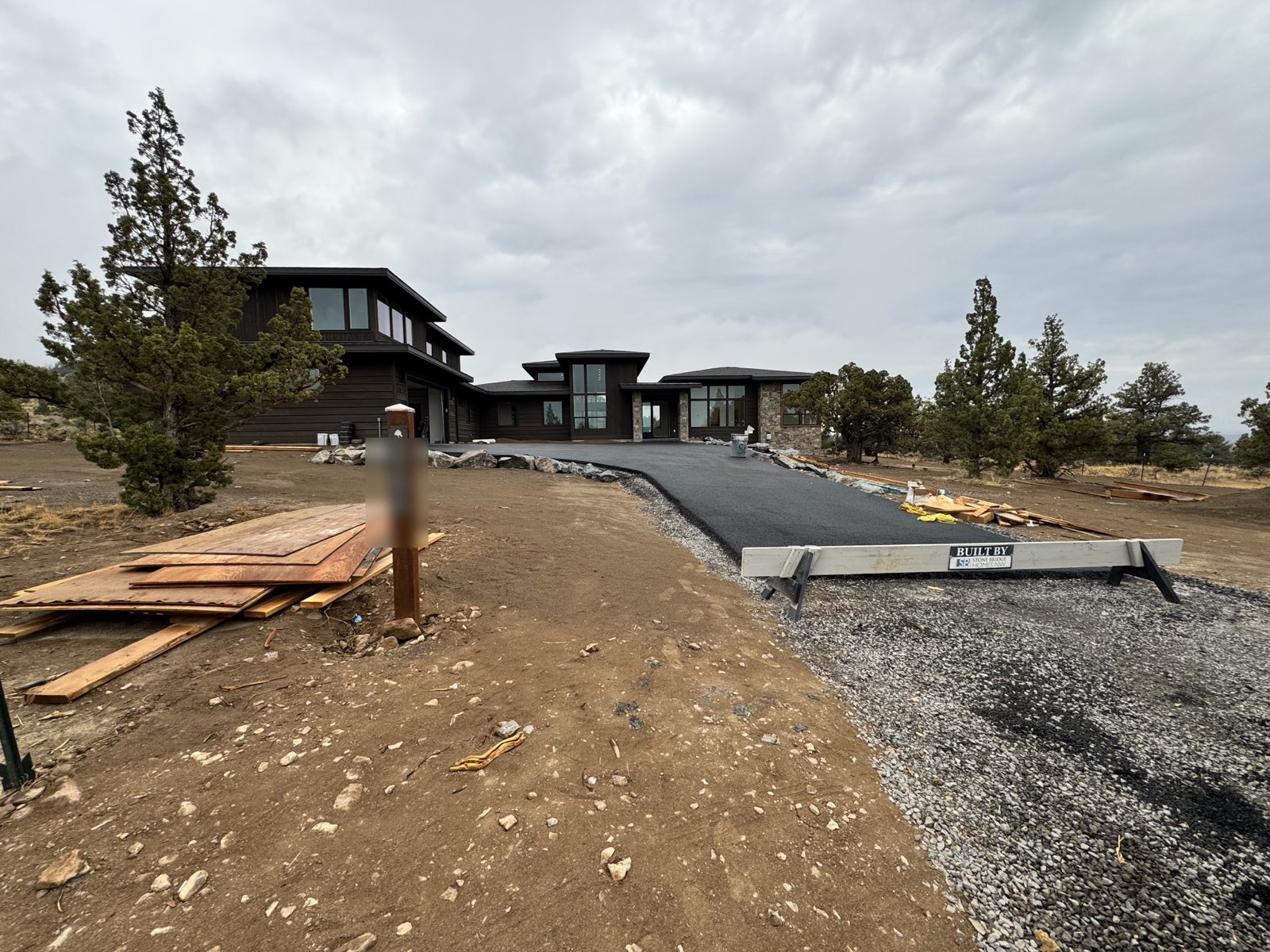 Contemporary custom home at Brasada Ranch in Powell Butte, Oregon, with dark-stained horizontal siding, deep eaves and stone veneer, exterior completed by Keystone Painting LLC